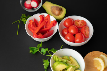 top view assorted sliced fresh vegetables in white bowls, ingredients for cooking salads