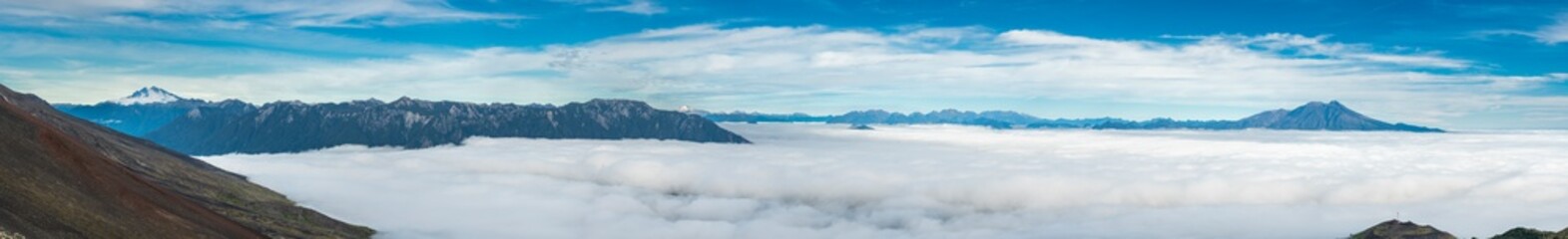 Amazing panoramic view from Osorno Volcano to an awe sea of clouds scenery on an amazing forest with Patagonia mountain range on the far distance dominated by Cerro Tronador mountain on the left