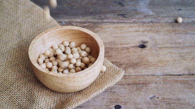Video footage of fresh raw soybeans pouring into wooden bowl with soy bean on gunny sack cloth, copy space, full high defination resolution, 29.97 frame per second, slowmotion
