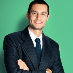 Happy businessman with crossed arms, on green