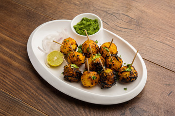 Tandoori aloo are roasted potatoes with Indian spices. It's a party appetiser served with green chutney. selective focus
