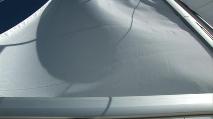 White sails fluttering in the wind of moving sailing yacht on background of blue sky during sea journey. Yachting as an relaxation active lifestyle.