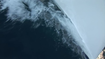 Nose and sides of white moving yacht cuts waves of water surface. Yachting sport, sea journey and regatta as an active lifestyle.