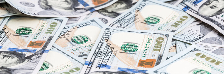 Background from dollars. Notes of one hundred American dollars are scattered across the background.