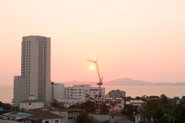 Building on the sea cost. Construction equipment at pink sunset. Real estate on the beach.