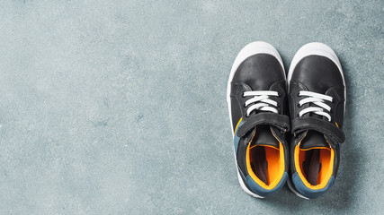 pair of new kids or adult sneakers on gray stone background, top view. Flat lay gray and yellow or...
