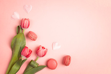 Tulip flowers with macarons on pink background. Place for text.