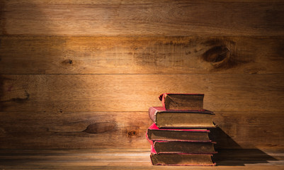 ray of light falling on pile of old books on wooden table, still life photography