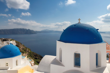 Fototapeta na wymiar Santorini, Greece. Spectacular view of Greek orthodox church with blue domes and sea in Oia town, Santorini island, Greece.