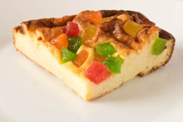 A piece of cottage cheese casserole with candied fruits on a white plate. Close up.