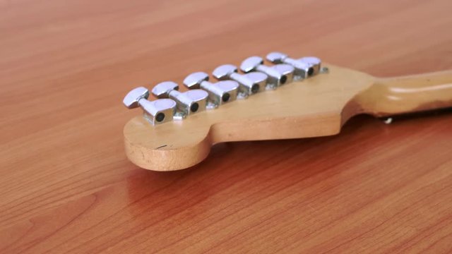 Slide motion of old electric guitar with a fine pattern of guitar strings placed on a wooden floor table