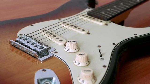 Slide motion of old electric guitar with a fine pattern of guitar strings placed on a wooden floor table