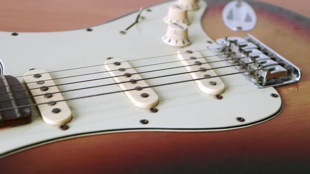 Slide motion of old electric guitar with a fine pattern of guitar strings placed on a wooden floor table