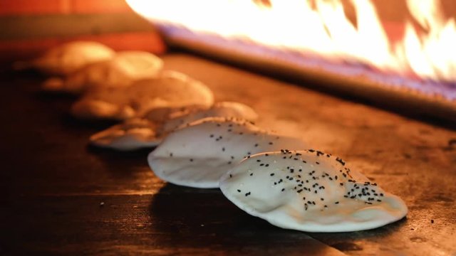 Pita Bread In Oven. Pita or pide bread covered with egg and sesame on on wooden oar in oven or stove. Bakery or bakehouse concept image.