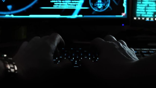 Close up of the hands of a hacker cyber criminal, typing rapidly on a keyboard