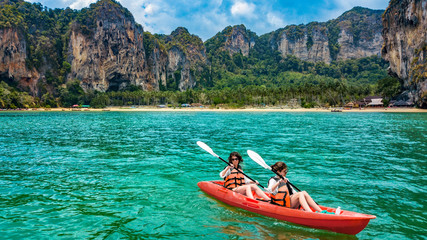 Fototapeta na wymiar Family kayaking, mother and daughter paddling in kayak on tropical sea canoe tour near islands, having fun, active vacation with children in Thailand, Krabi
