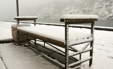 snow-covered bench by the river