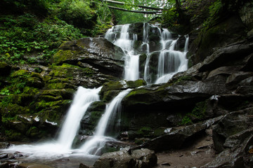 Large cascading waterfall in a mountain forest.