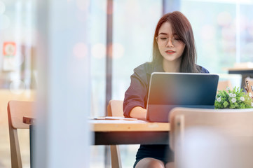 Portrait of young woman working at co-working space with her laptop computer.