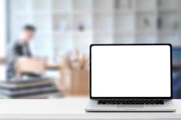 Mockup laptop with blank screen on white table at co working space room.