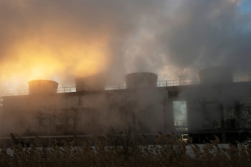 Fototapeta na wymiar Steam from the old factory in the sunset sun.