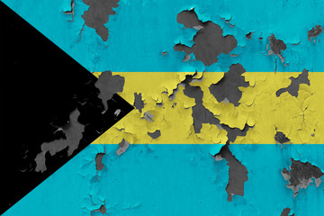 Close up grungy, damaged and weathered Bahamas flag on wall peeling off paint to see inside surface.