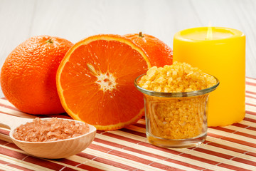 Cut orange, candle, wooden spoon and glass bowl with sea salt.