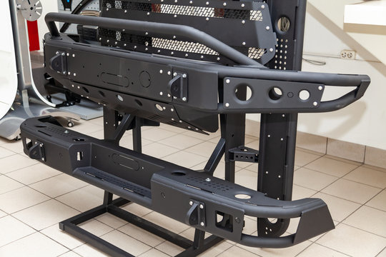 Stand For Demonstration Of Car Body Elements Reinforced For Off-road And Made Of Metal, Such As Bumper, Steps And Black Grille In The Workshop For The Installation And Tuning Of SUV Vehicles.