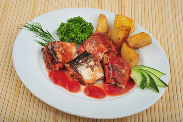 Plate with sardines tomatoes and aromatic herbs on a table