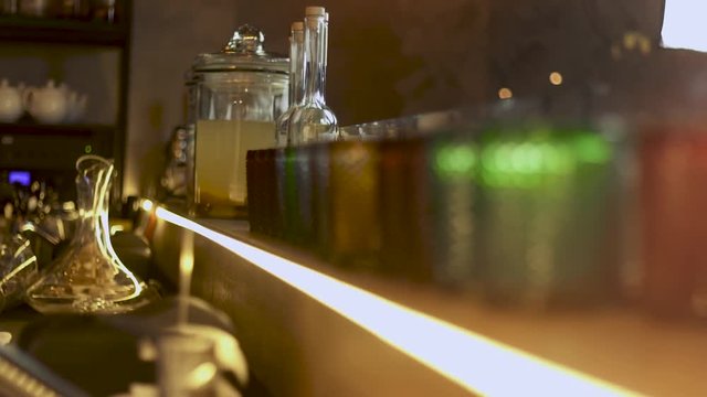 Clean faceted colored glasses and a bottle of lemonade on the bar. View from inside the bar