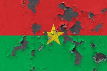 Close up grungy, damaged and weathered Burkina Faso flag on wall peeling off paint to see inside surface.