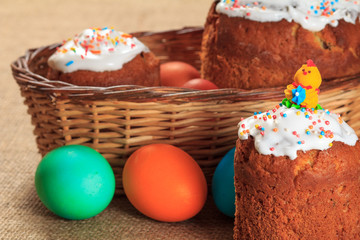 Easter cake and colorful Easter eggs in wicker basket.