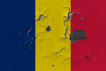 Close up grungy, damaged and weathered Chad flag on wall peeling off paint to see inside surface.