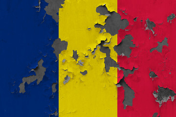 Close up grungy, damaged and weathered Chad flag on wall peeling off paint to see inside surface.