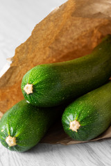 Organic courgette in a brown paper bag on grey wood.  Recycle packaging concept.  No plastic waste