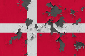 Close up grungy, damaged and weathered Denmark flag on wall peeling off paint to see inside surface.