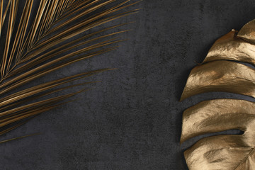 golden palm and monstera leaves on dark grey background