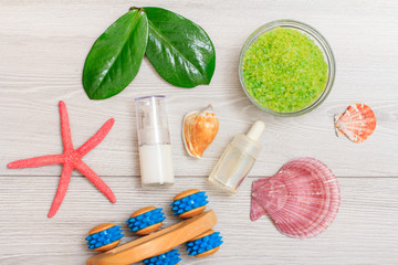 Syringe with eye cream, bottles with cream for face skin and aromatic oil, hand massager, bowl with sea salt on boards.