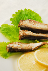 Pan-fried spiced sprats with lemon, salad on a plate