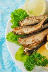 Pan-fried spiced sprats with lemon, salad on a plate
