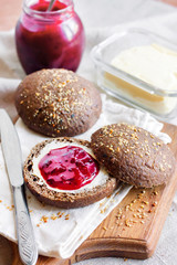Homemade rye buns with linseeds, sesame and white poppy seeds served with butter and Jostaberry jam