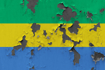 Close up grungy, damaged and weathered Gabon flag on wall peeling off paint to see inside surface.