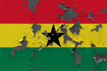 Close up grungy, damaged and weathered Ghana flag on wall peeling off paint to see inside surface.