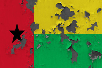 Close up grungy, damaged and weathered Guinea Bissau flag on wall peeling off paint to see inside surface.