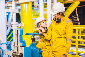 Young man and a little boy are both in a yellow work uniform, glasses, and helmet in an industrial environment, oil Platform or liquefied gas plant