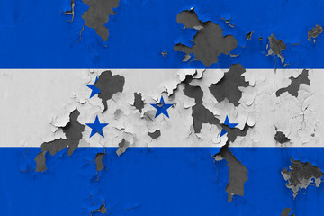 Close up grungy, damaged and weathered Honduras flag on wall peeling off paint to see inside surface.