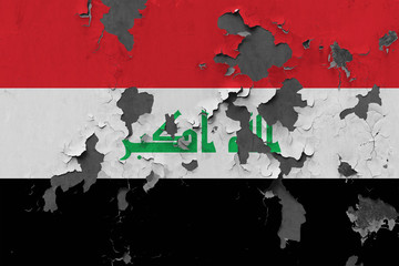 Close up grungy, damaged and weathered Iraq flag on wall peeling off paint to see inside surface.