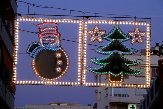 Snowman and tree Christmas light decoration suspended across the street at night, Fuengirola, Spain.