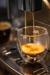 glass mugs with coffee in a coffee machine,cooking process, close-up
