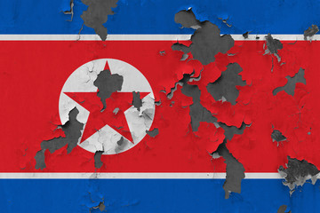 Close up grungy, damaged and weathered North Korea flag on wall peeling off paint to see inside surface.